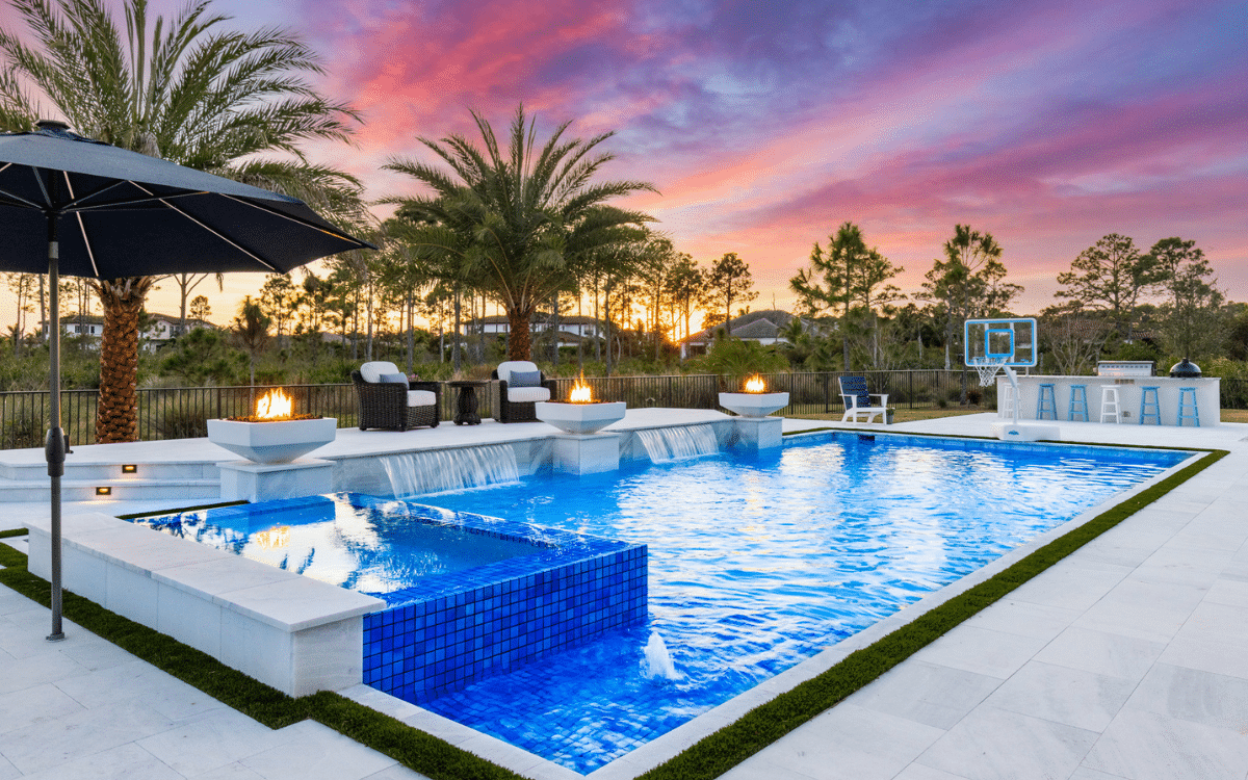 Fire bowls burning beside a custom pool at dusk
