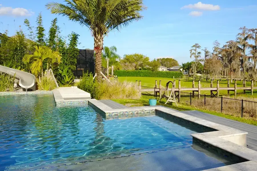 Luxury custom pool slide built into a backyard pool