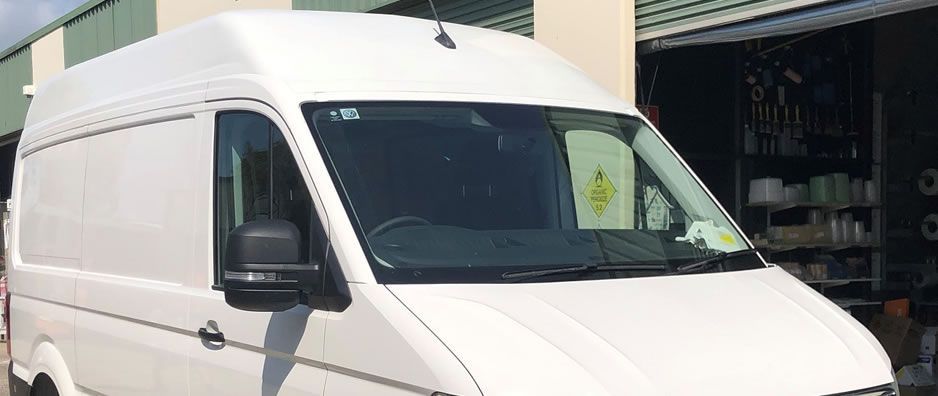 A white van is parked in front of a building.