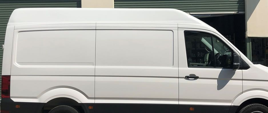 A white van is parked in front of a building.