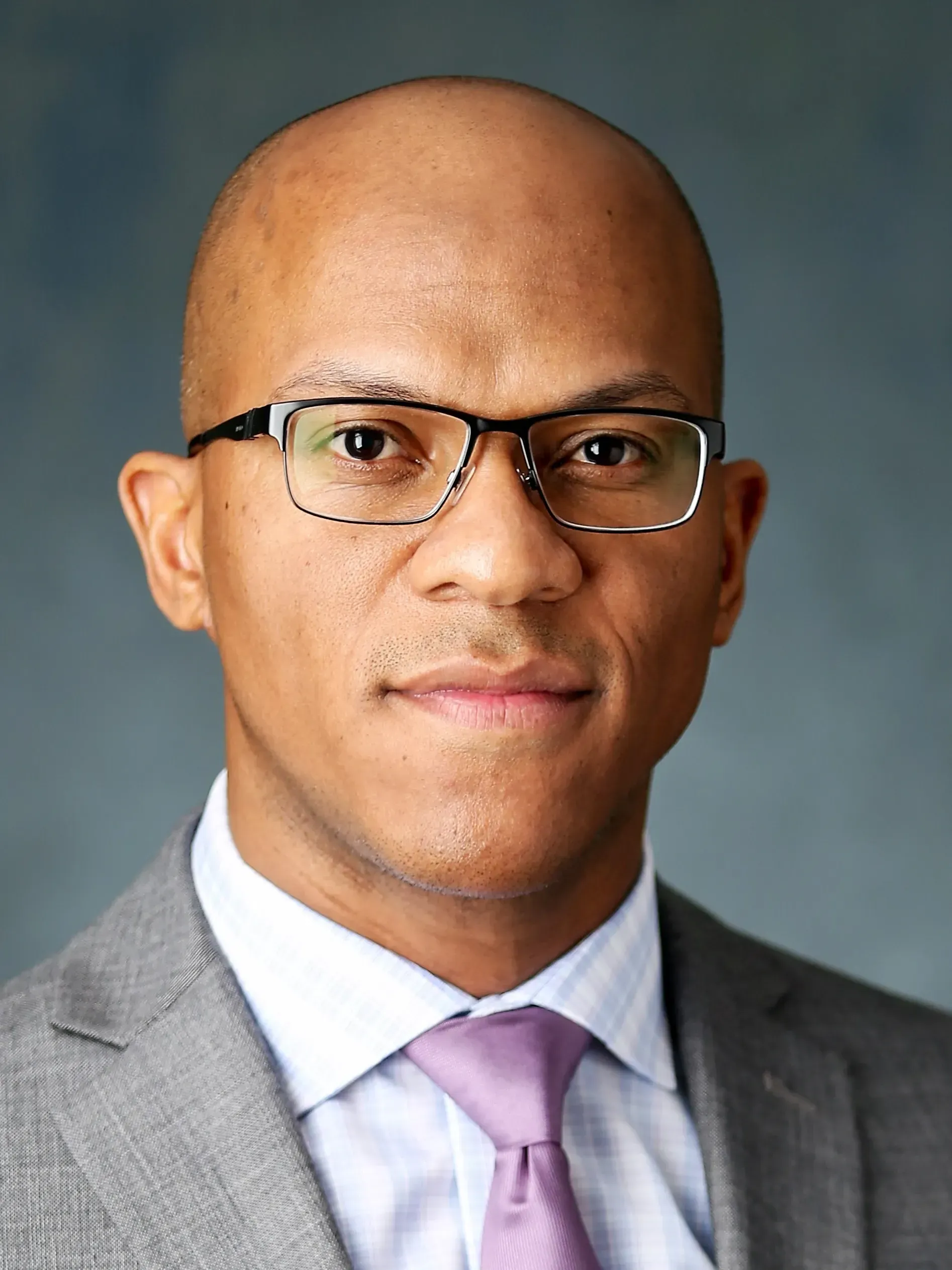 A bald man wearing glasses and a suit and tie