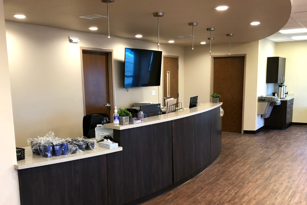 A reception desk in a hospital with a tv on the wall.