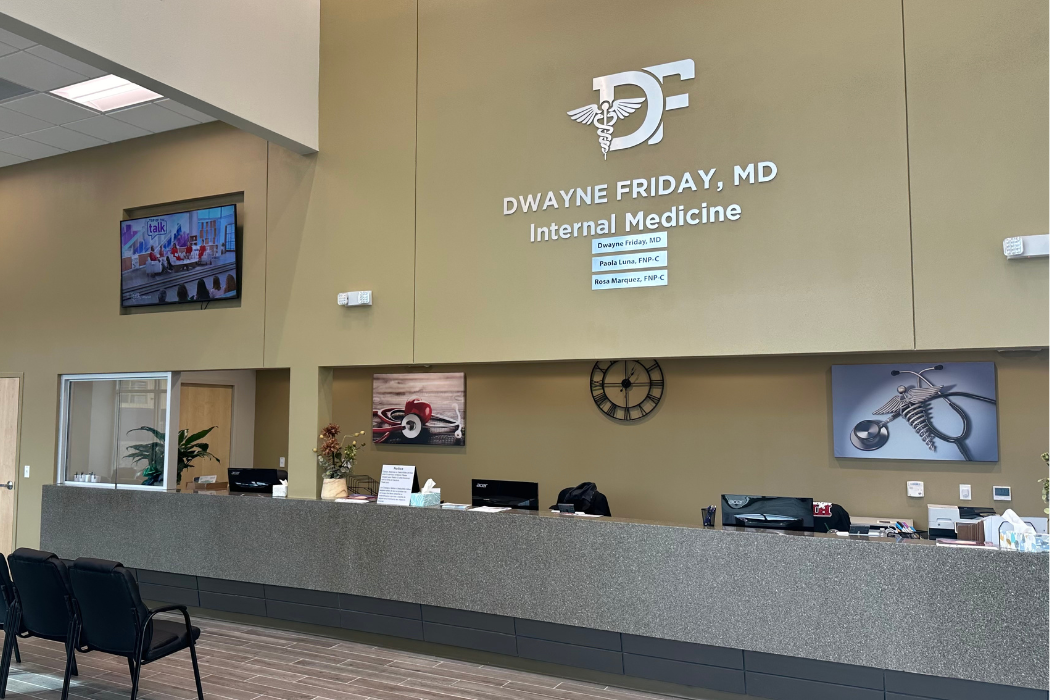 The front desk of a hospital with a clock on the wall.