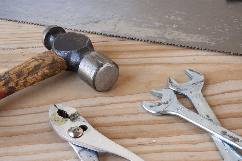 A Hammer, Pliers, Wrenches And A Saw Are On A Wooden Table — All Trades Equipment In Lismore, NSW