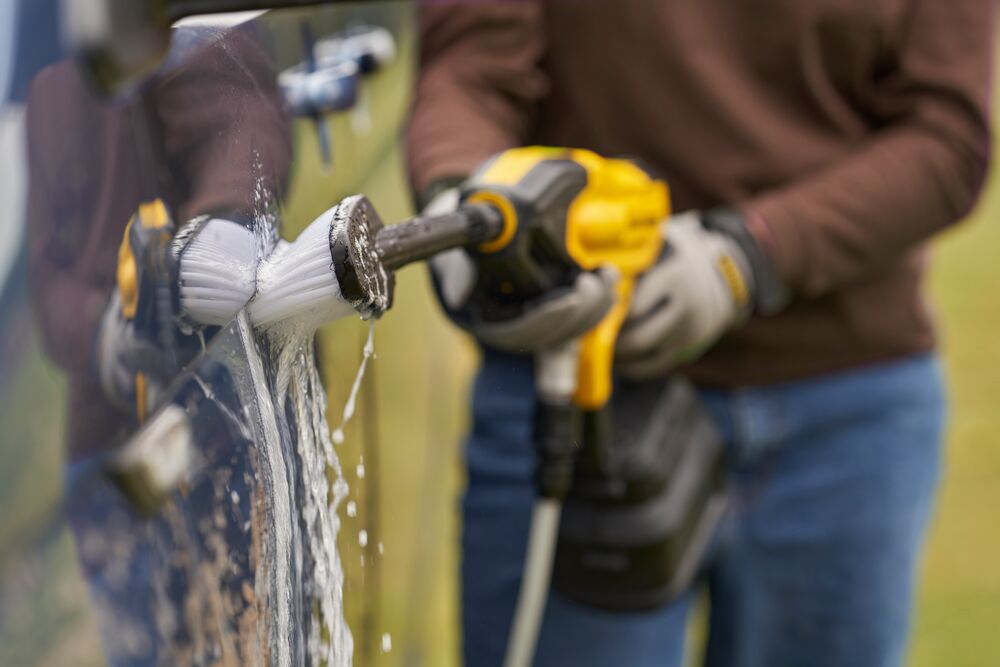 A Man Is Cleaning A Car With A Brush — All Trades Equipment In Lismore, NSW