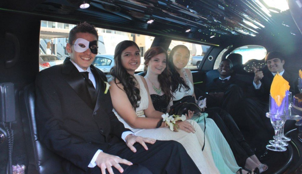 A group of people wearing masks are sitting in a limousine