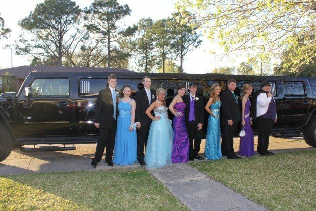 A group of people standing in front of a black limousine