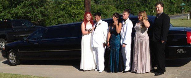 A group of people standing in front of a black limousine.