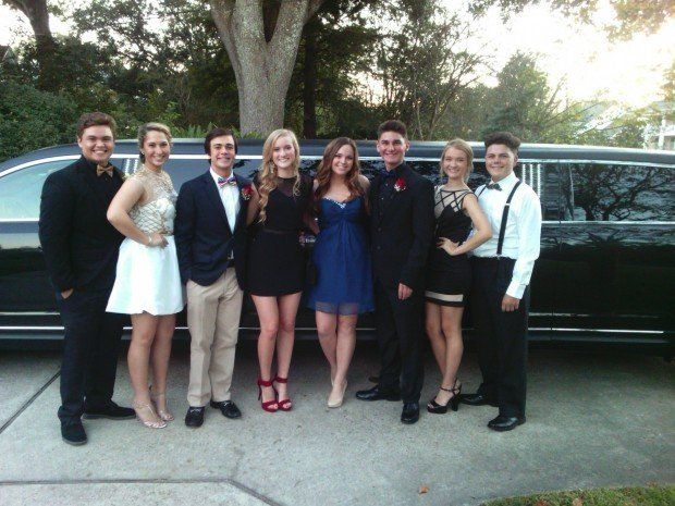 A group of people standing in front of a black limousine