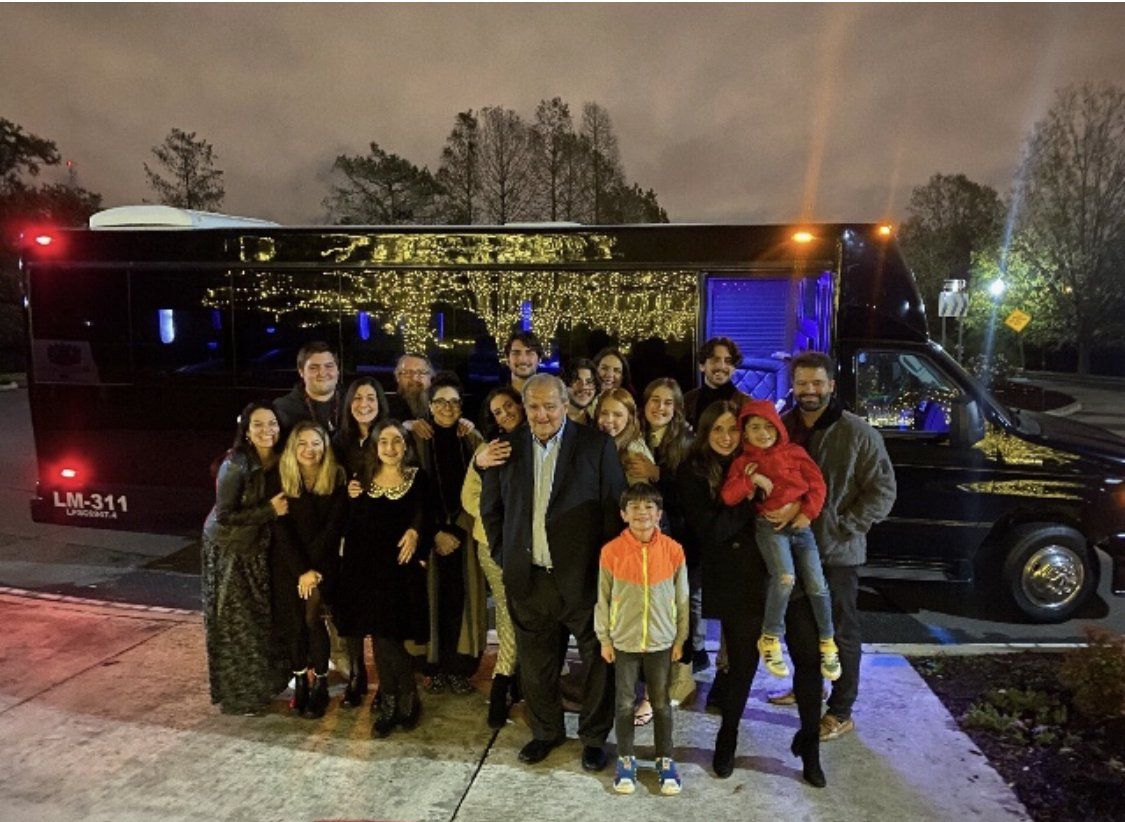 A large group of people are posing for a picture in front of a shuttle bus.