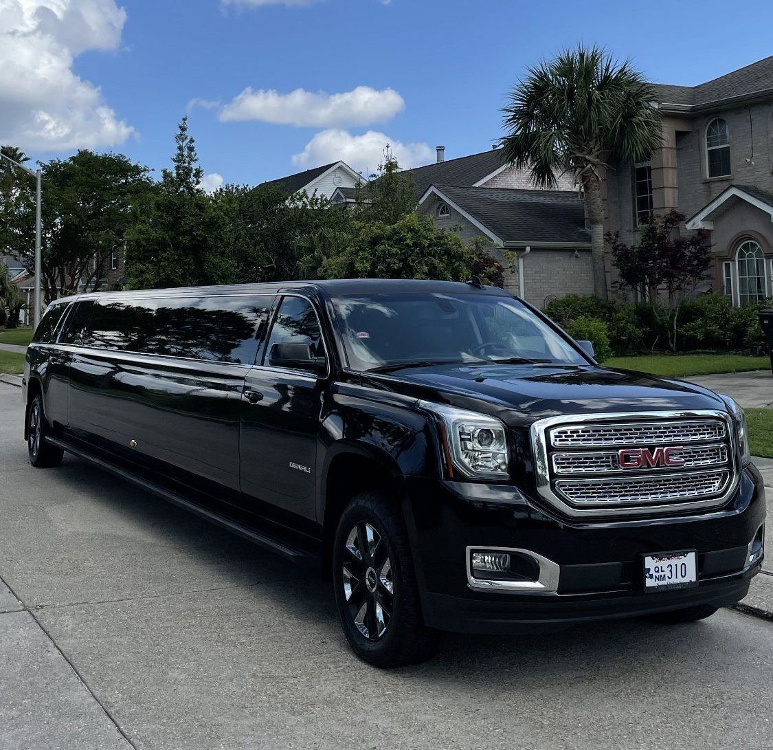 A black gmc limousine is parked on the side of the road