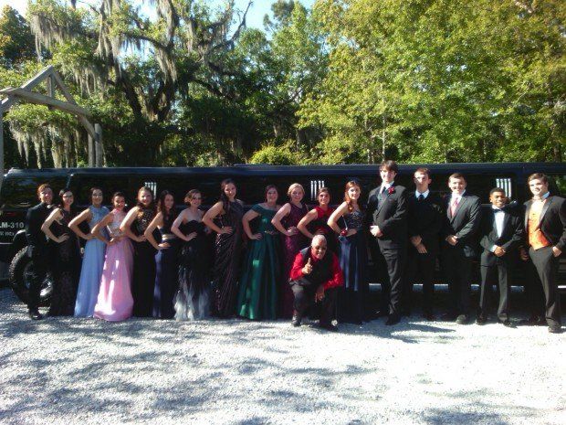 A group of people posing in front of a limousine