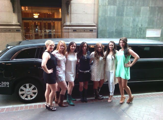 A group of women are posing for a picture in front of a limousine that says 300 miles