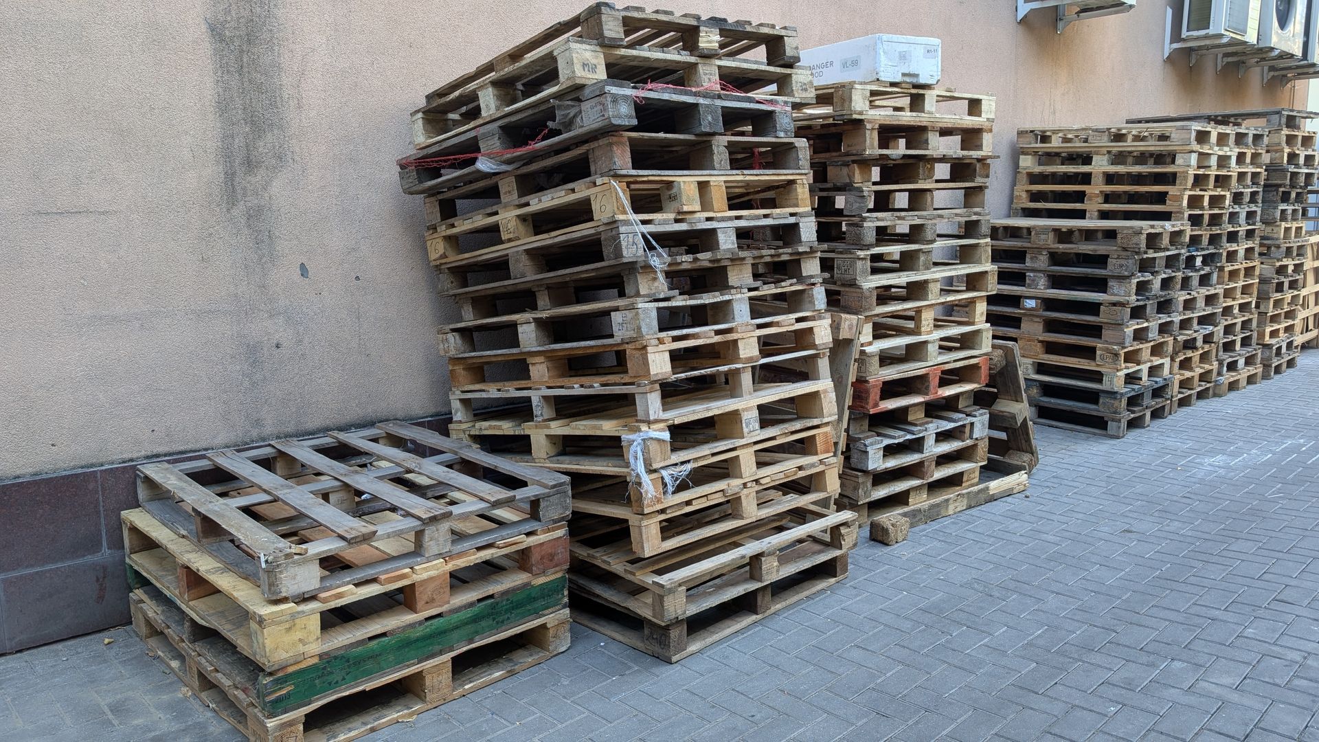 Wooden pallets stacked in a warehouse setting, shelves filled in the background.