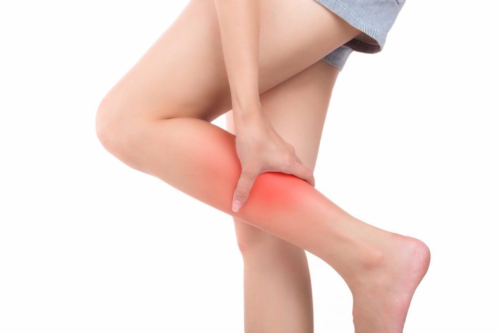 A woman is holding her leg in pain.
