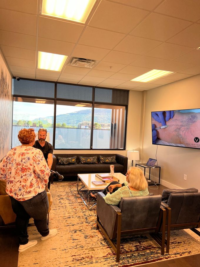 A group of people are sitting in a living room with a couch and chairs.