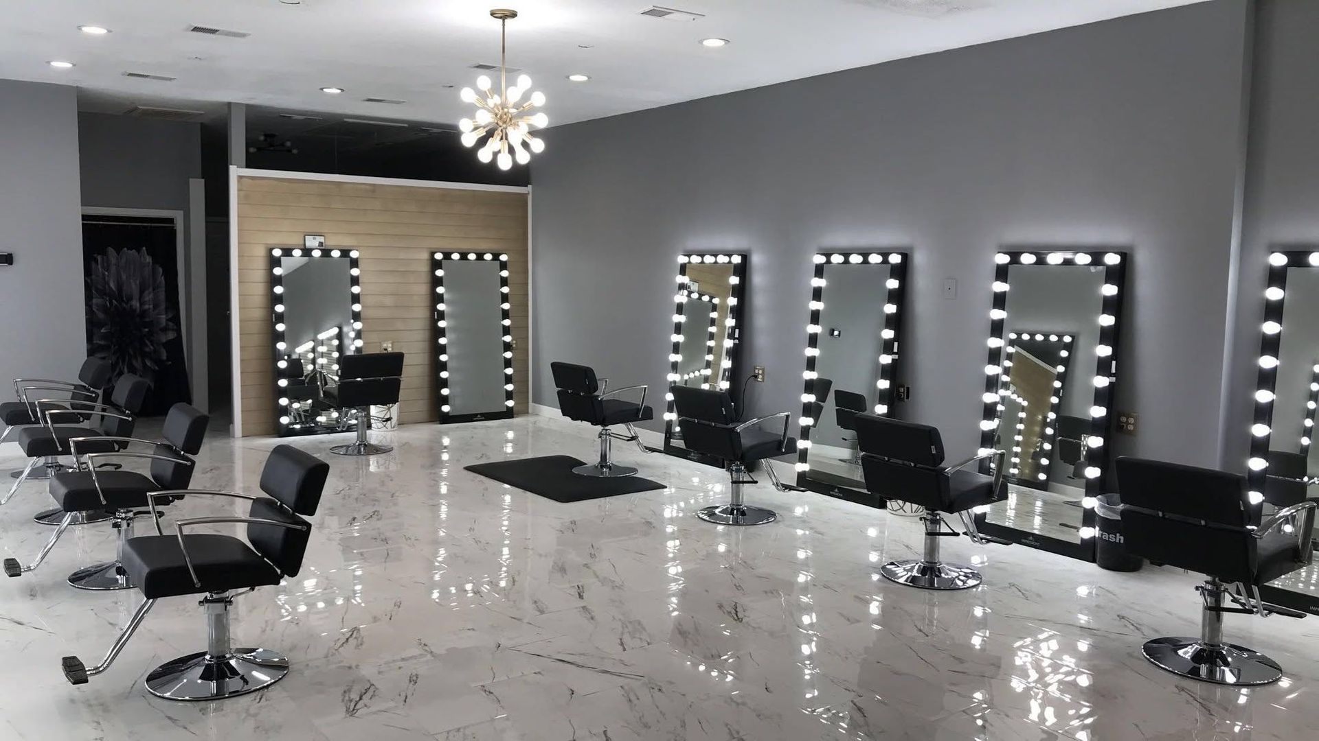 Modern salon interior with illuminated mirrors, styling chairs, and glossy white floors