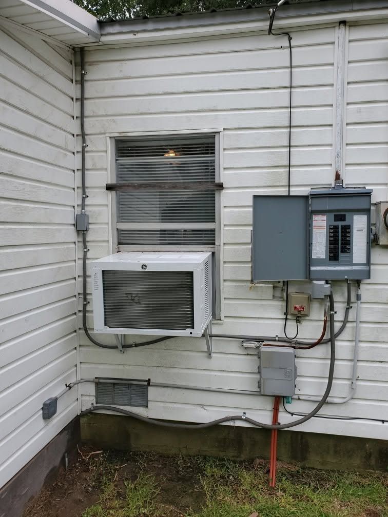 Exterior wall with window AC unit and electrical meter boxes on a white house side