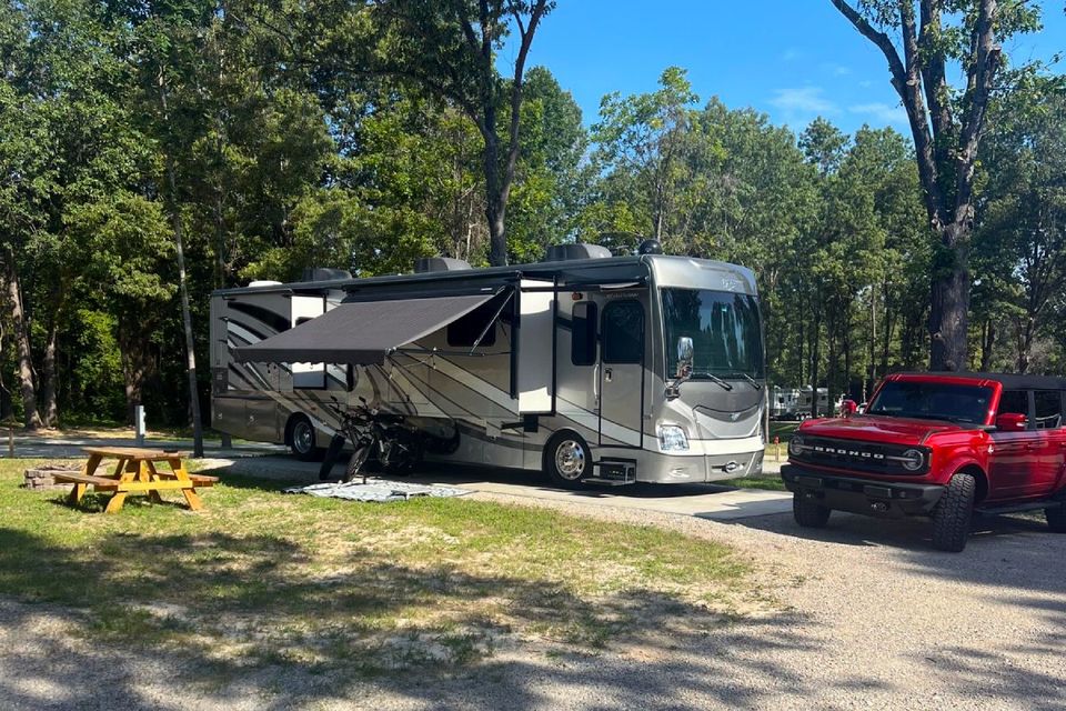A rv is parked in a campground next to a red truck.