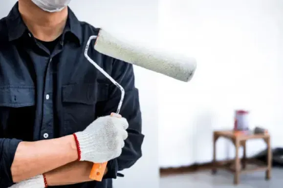 A man wearing a mask is holding a paint roller.