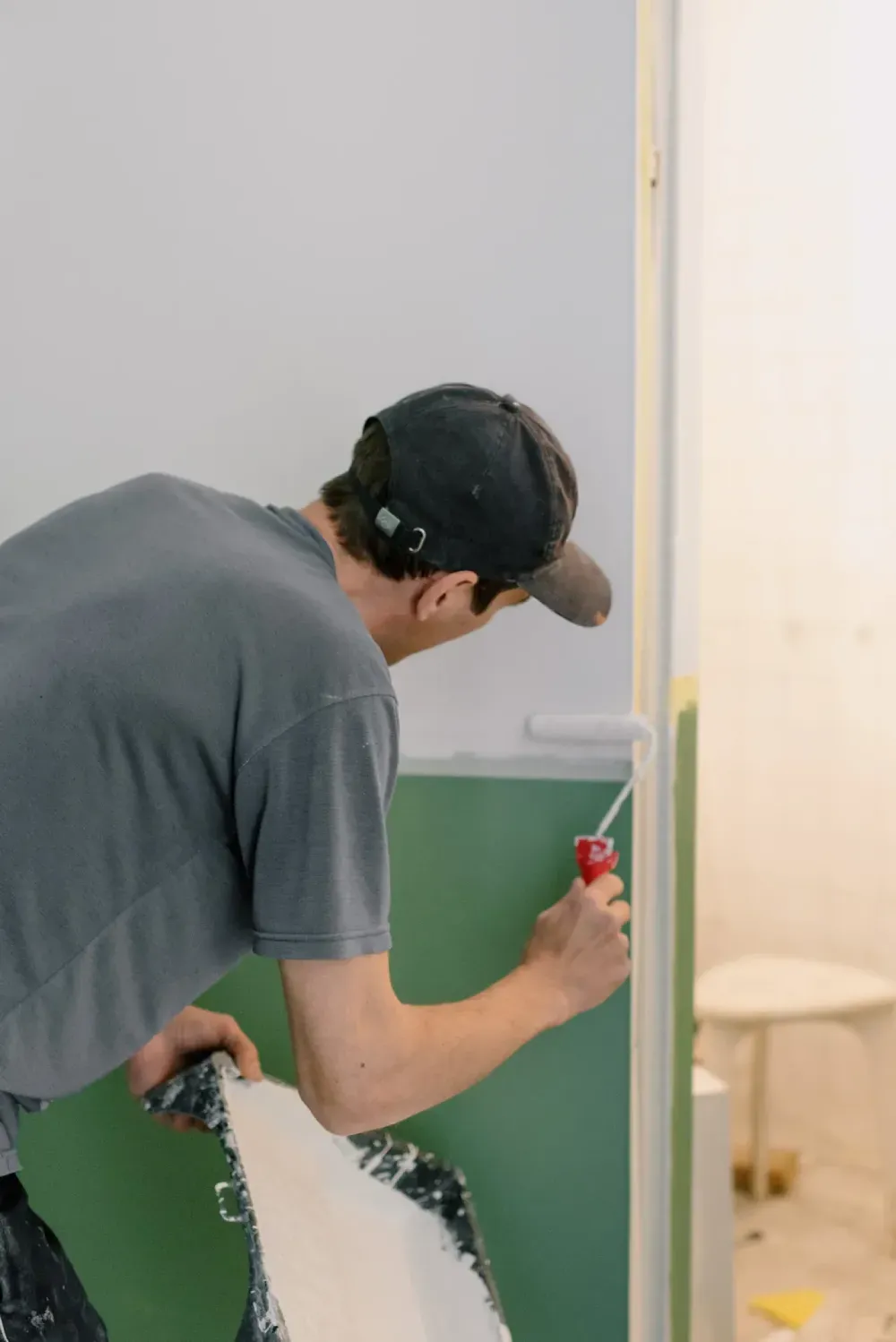 A man is painting a wall with a screwdriver.