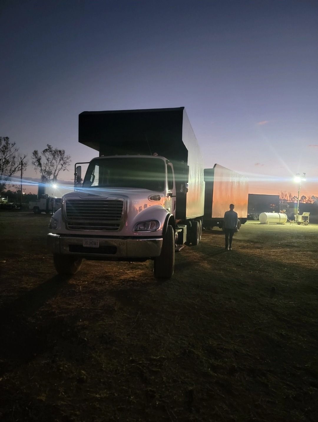A white truck is parked in a field at night.