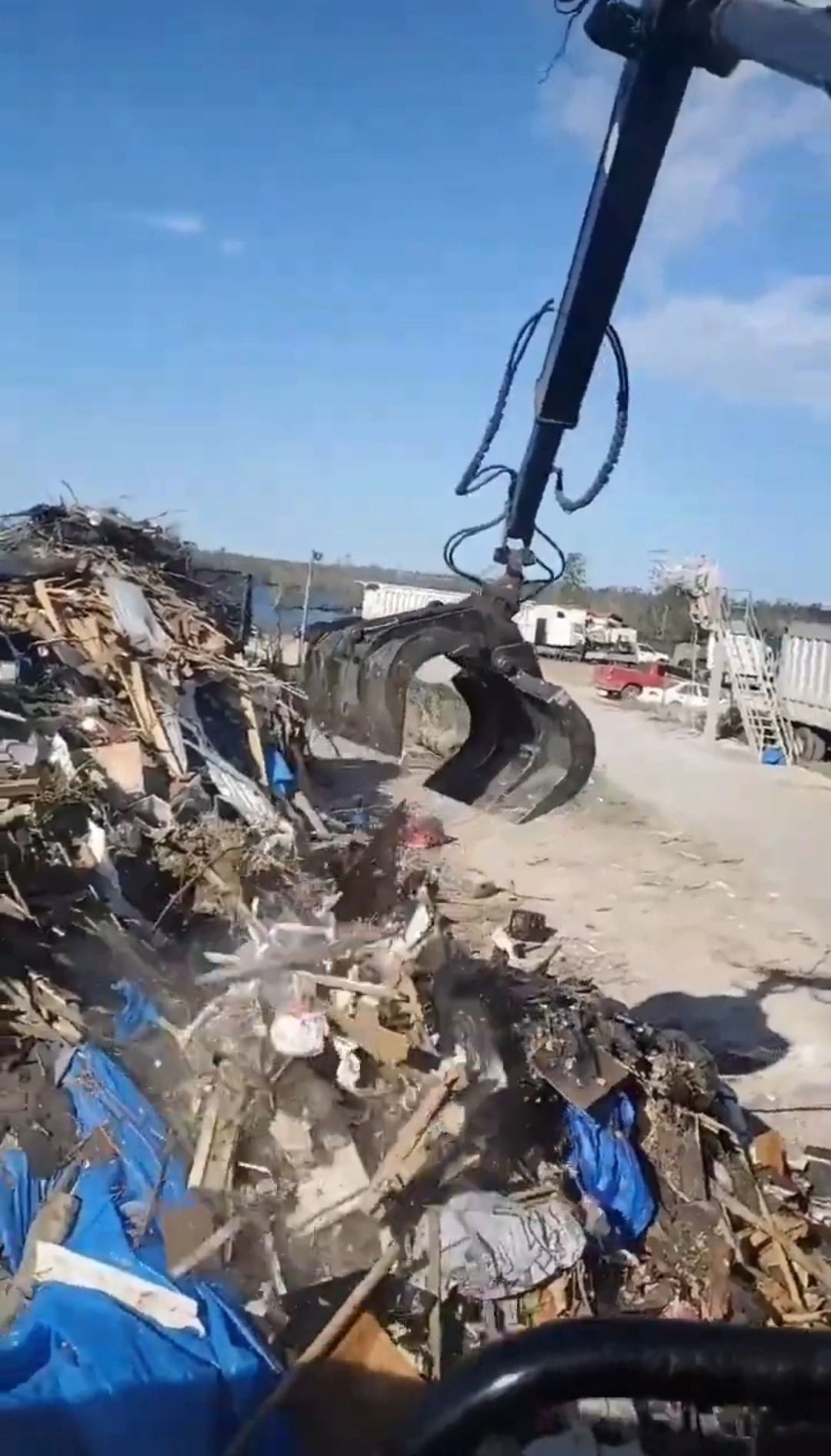 A large yellow excavator is demolishing a building.