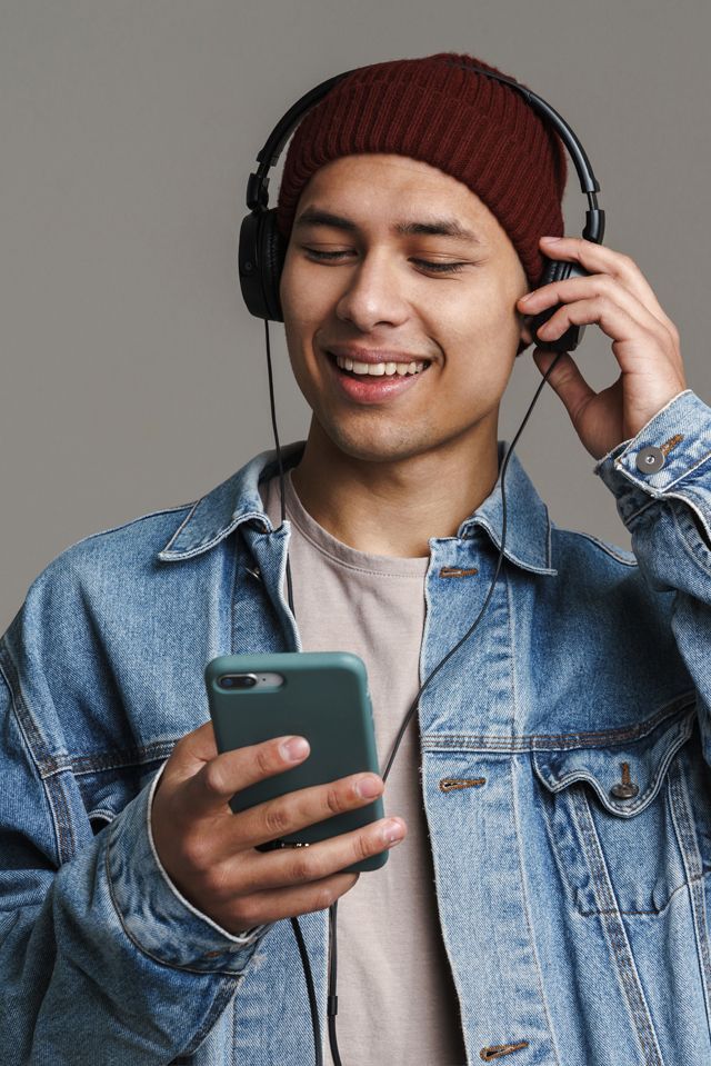 A man wearing headphones is listening to music on his phone.