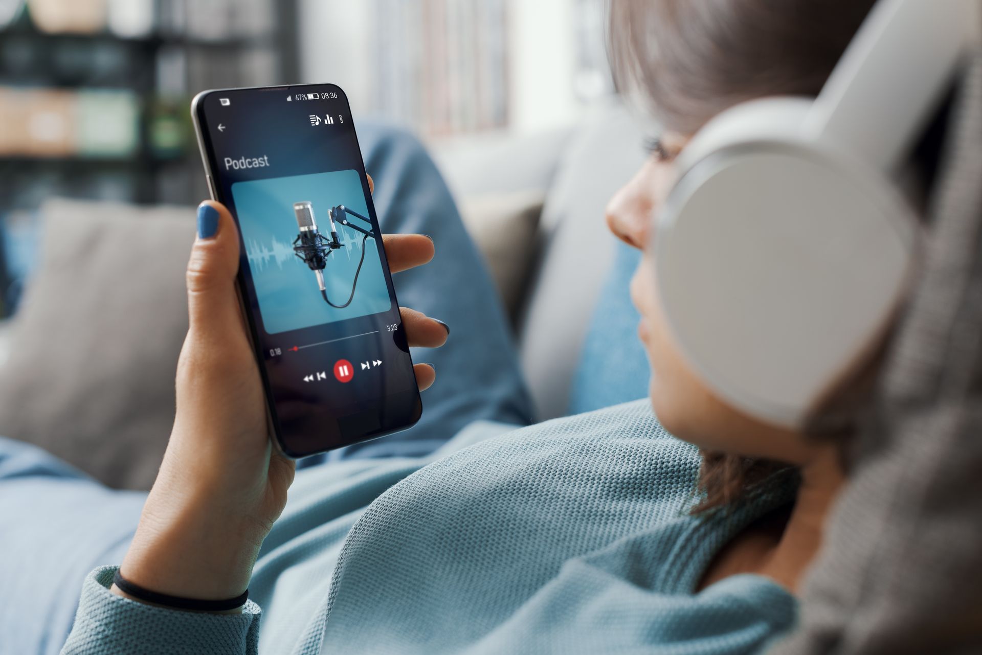 A woman is listening to music on her phone while wearing headphones.