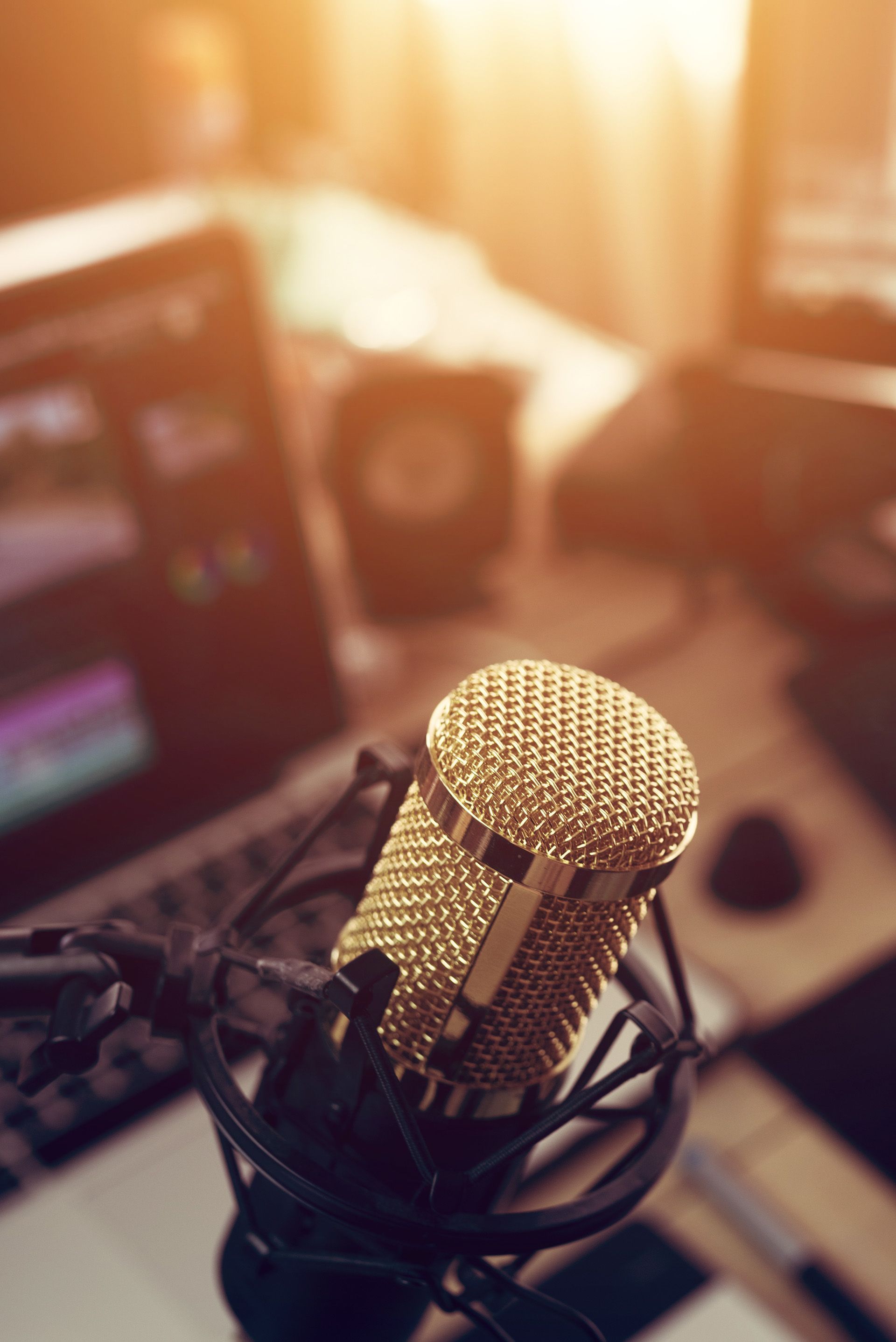 A microphone is sitting on a desk in front of a laptop.