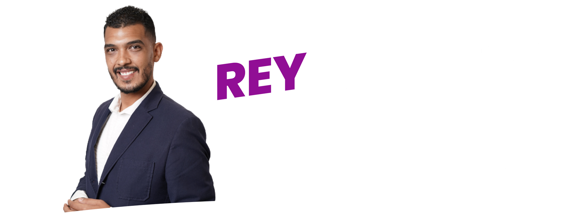 A man in a suit is standing in front of a white background with the word rey.