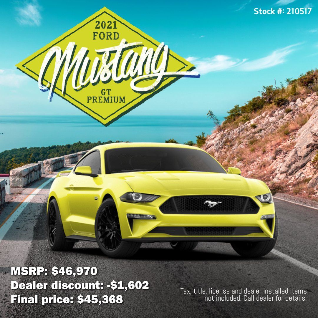 A yellow ford mustang is driving down a road