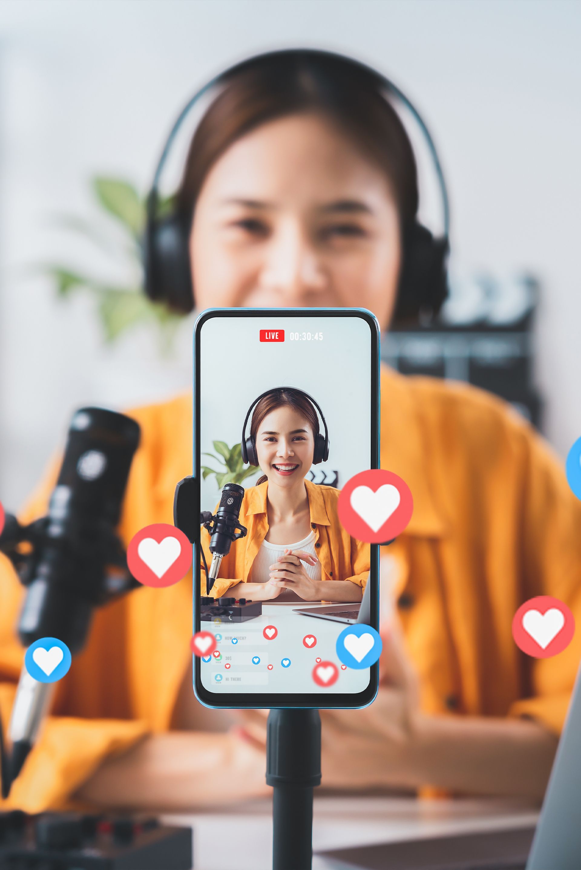 A woman wearing headphones is recording a video on her cell phone.