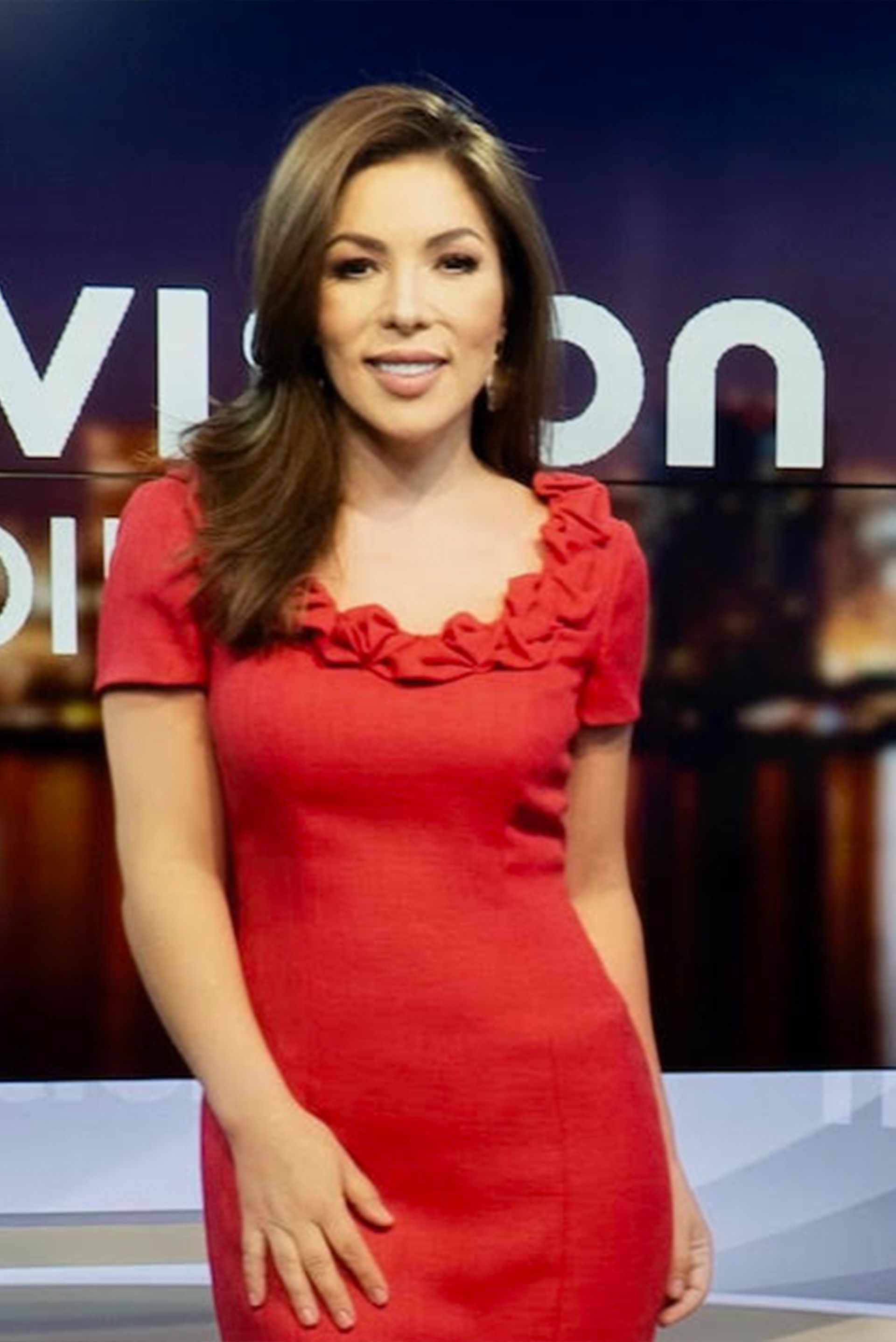 A woman in a red dress is standing in front of a sign that says vision