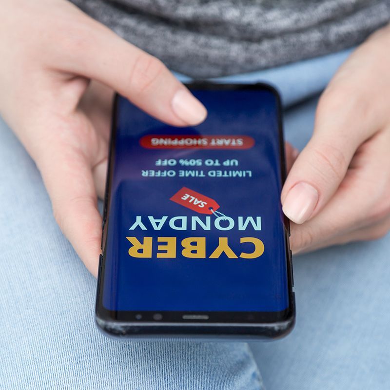 A person is holding a cell phone that says cyber monday