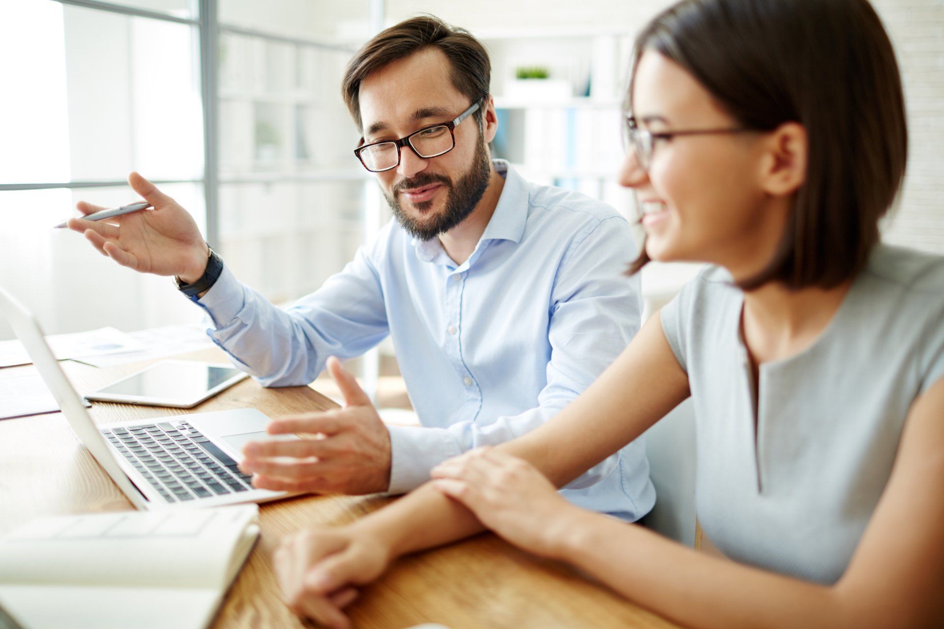 A man and woman sit at a desk as they discuss a Hispanic marketing plan for their business.