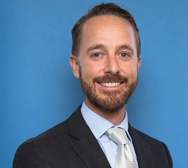 A man in a suit and tie is smiling for the camera.