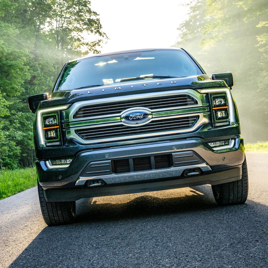 A black ford f150 is driving down a country road.