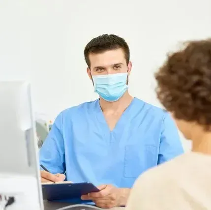 A doctor wearing a mask is talking to a patient.
