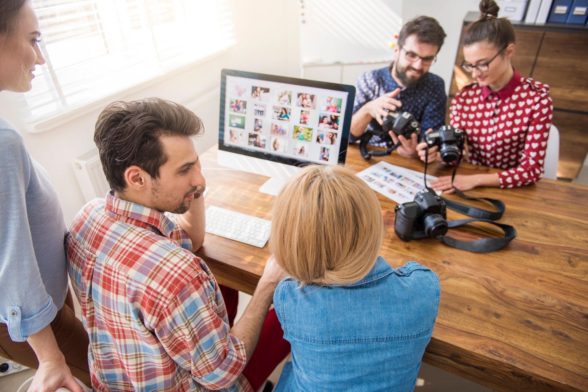 5 people working on a desk with a desktop