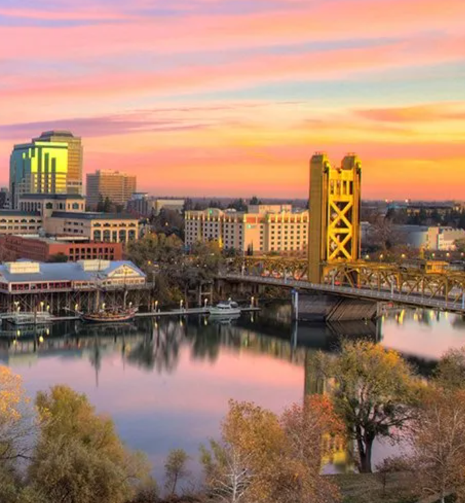 An aerial view of a bridge over a river in a city at sunset.