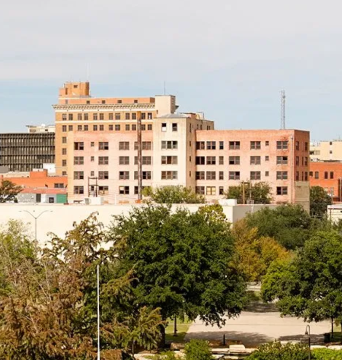 A large building with a lot of windows is surrounded by trees