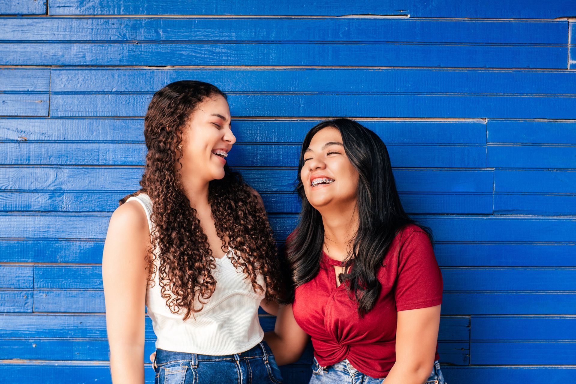 two hispanic friends with brackets laughing together