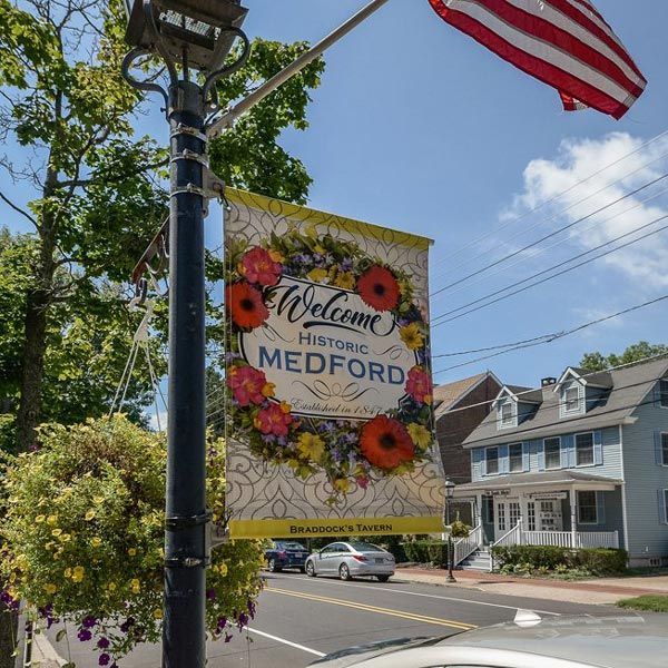 Welcome to historic Medford banner with flowers on a street beside a house and U.S. flag