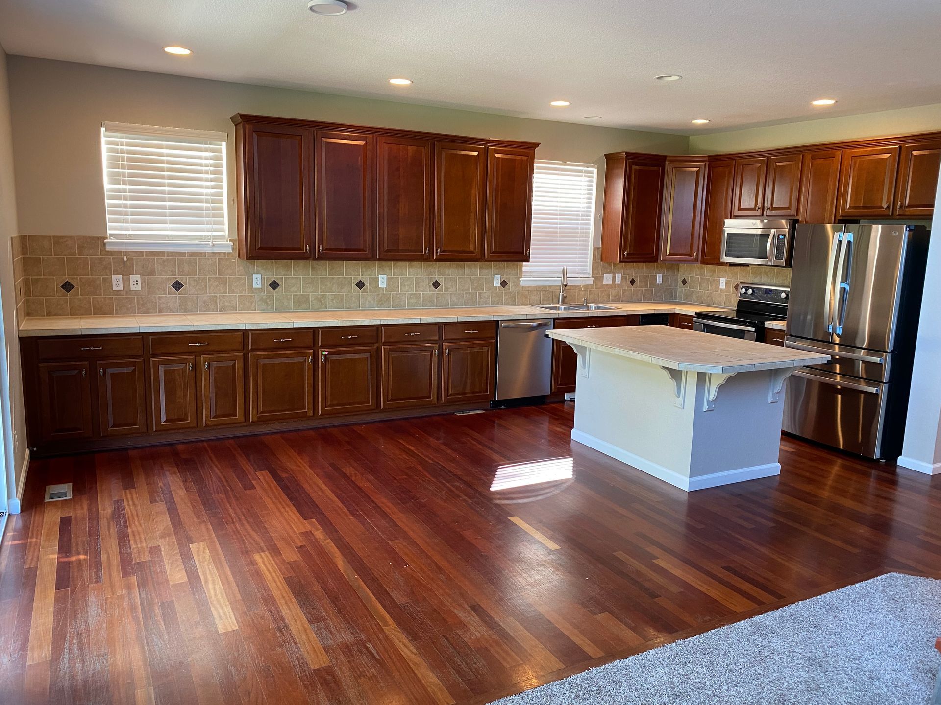 Kitchen with wood cabinets, countertops, and flooring, stainless steel appliances, and a central island.