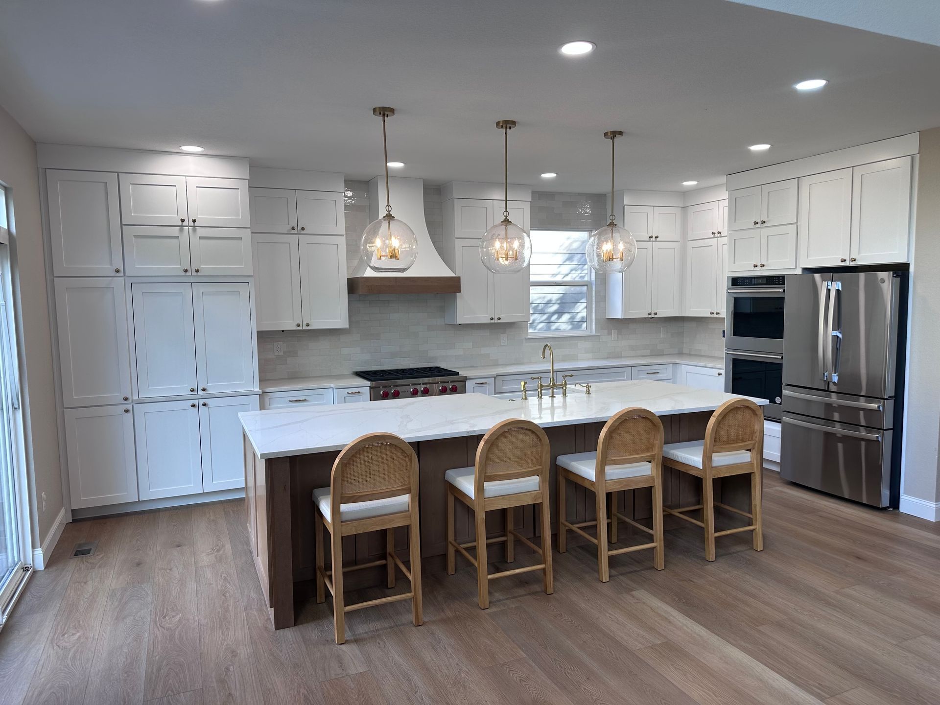 Modern kitchen with white cabinets, island with seating, stainless steel appliances, and hardwood floors.