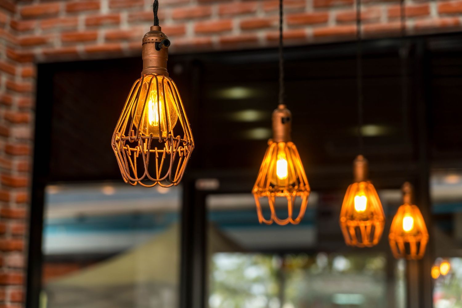 Warm hanging pendant lights glowing in a brick-walled interior above a window