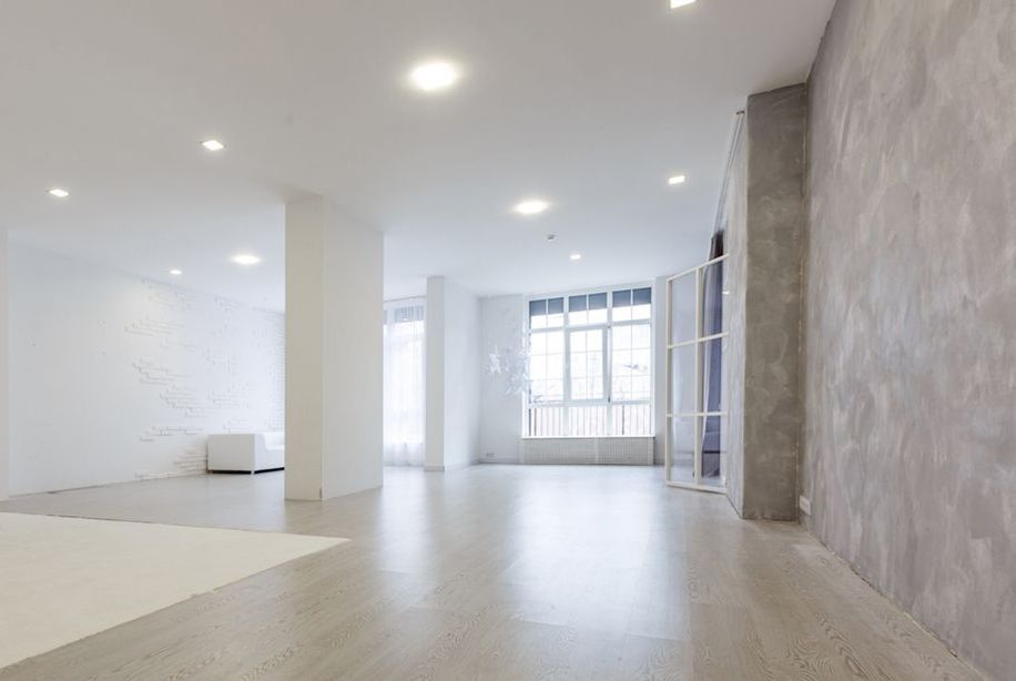 A large empty room with a wooden floor and white walls.