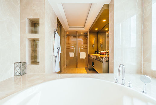 A luxurious bathroom with a large tub, a shower, and a vanity, all in shades of white and gold.