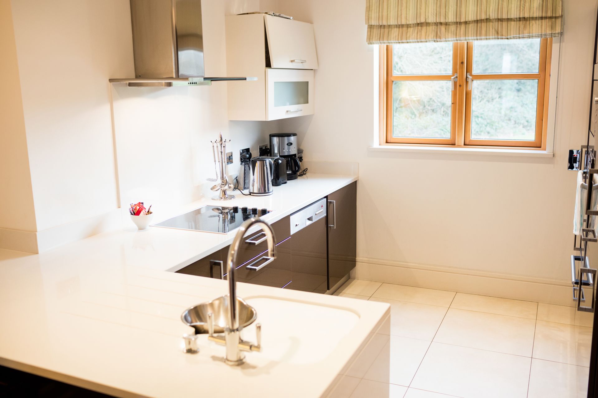 Bright modern kitchen with white island, dark cabinets, coffee maker, and a window letting in daylight